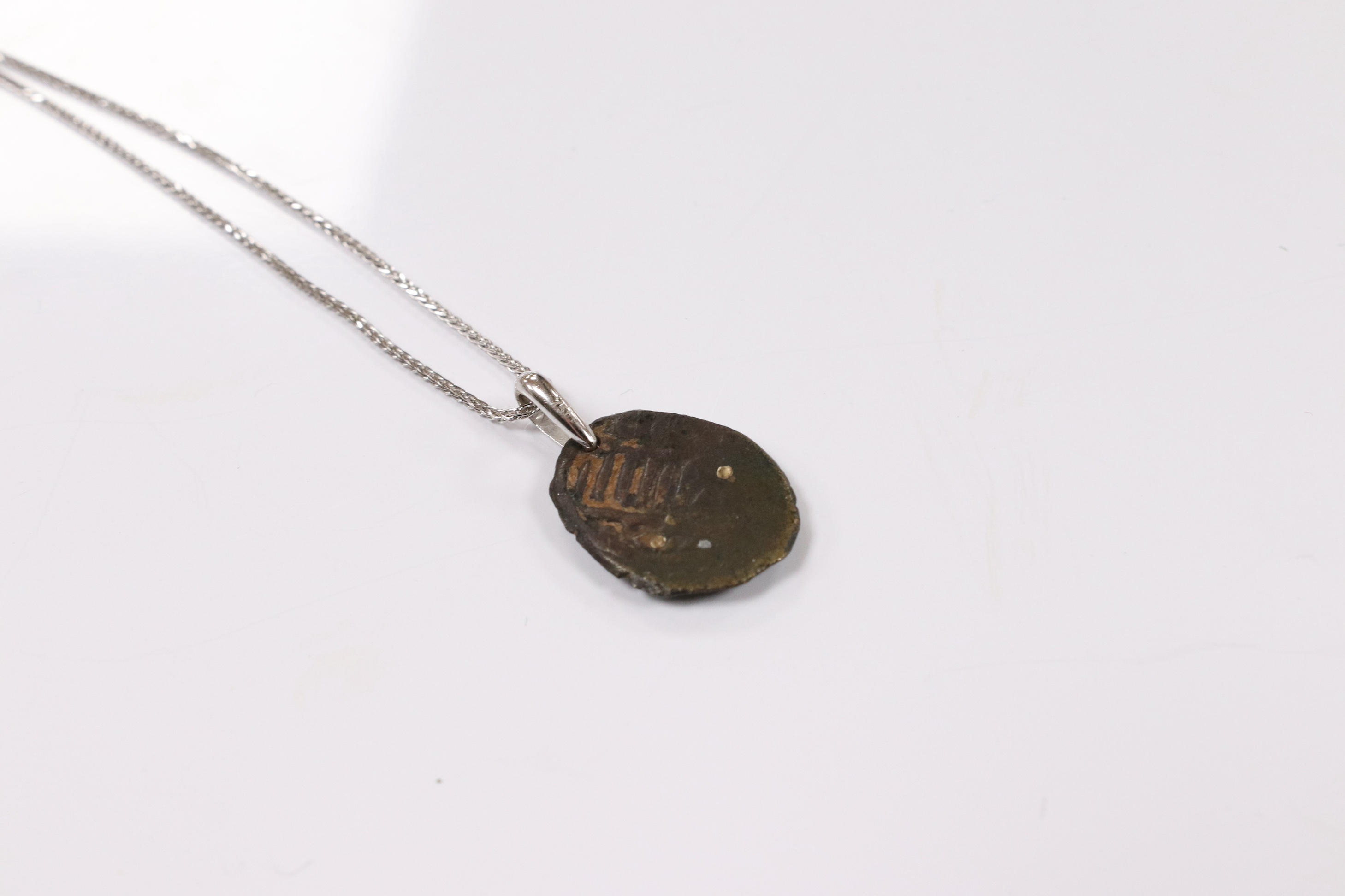 A modern 18k white metal mounted pendant, modelled as an ancient coin later mounted with brilliants, overall 25mm, on an Italian 18k white metal fine link chain, 44cm, gross weight 6 grams. Condition - poor to fair